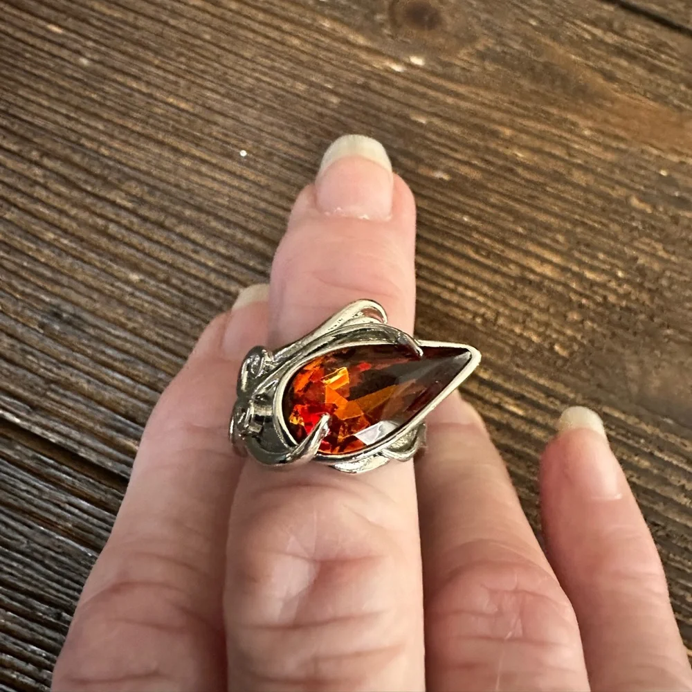 Ring in silver metal intricate with teardrop shaped amber color stone