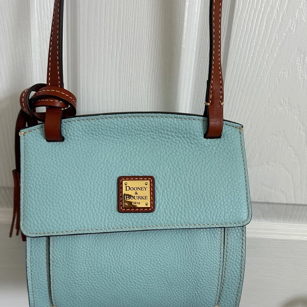 This is a Dooney & Bourke Pebble Grain East/West Flap Crossbody in a light blue